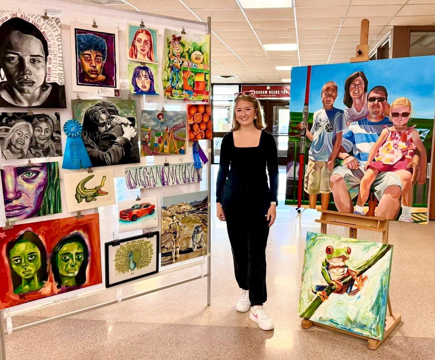 Woman standing in a hallway with art displayed on walls and shelves